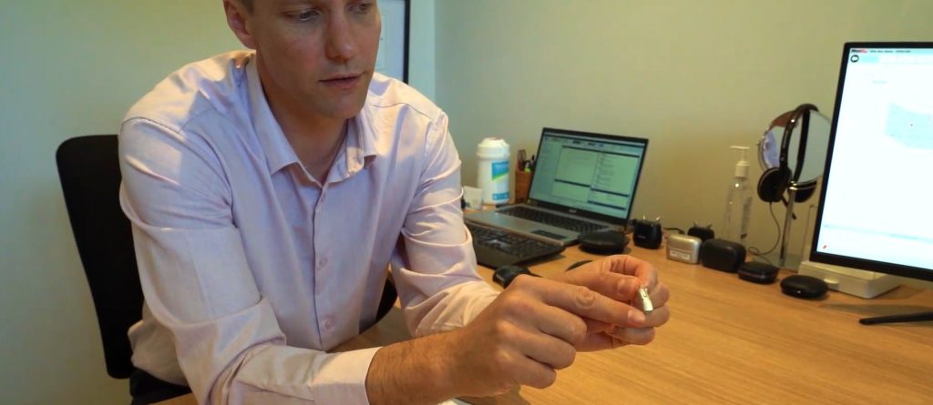 Hearing specialist demonstrating a hearing aid during consultation